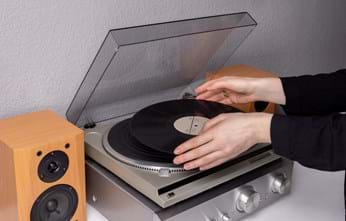 womans hands putting record on the record player